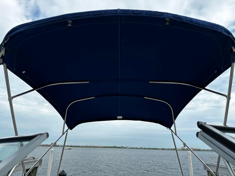 Slide: The Image of 2016 Crownline 285 SS boat with blue bimini top on a calm lake. - 18
