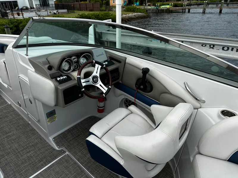 Slide: The Image of 2016 Crownline 285 SS boat cockpit with steering wheel and dashboard, docked by the water. - 38