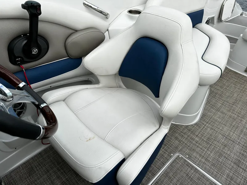 Slide: The Image of Captain's seat of a 2016 Crownline 285 SS boat with white and blue upholstery. - 48