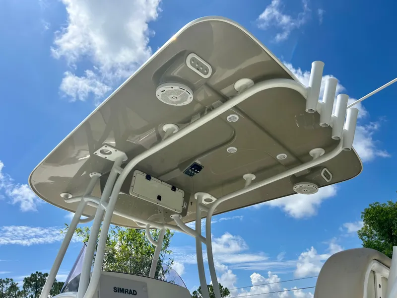 Slide: The Image of 2018 NauticStar 22 XS boat T-top with rod holders and speakers against blue sky. - 15