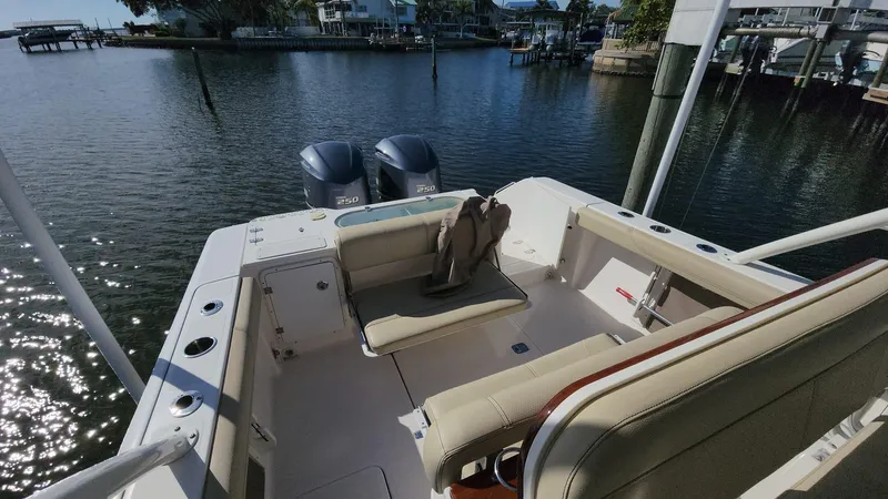 Slide: The Image of 2017 Pursuit S 280 Sport boat interior with seating, docked by a serene waterfront. - 49