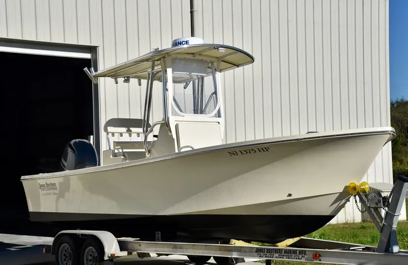 The Image of 2024 Jones Brothers Cape Fisherman 23 boat on a trailer outside a building. - 0