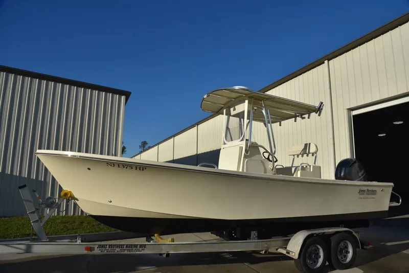 Slide: The Image of 2024 Jones Brothers Cape Fisherman 23 boat with two people fishing in open water. - 12