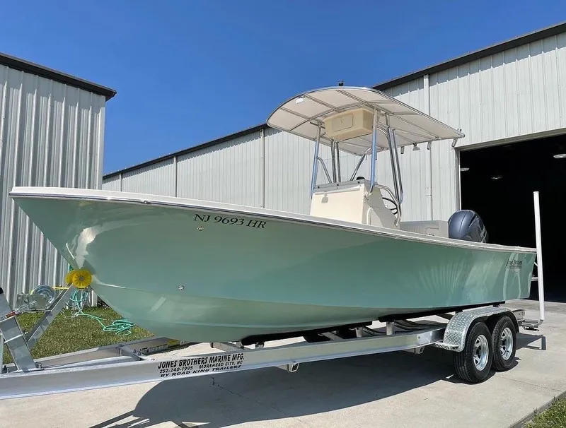 Slide: The Image of 2025 Jones Brothers Cape Fisherman 23 boat on trailer near metal building. - 2