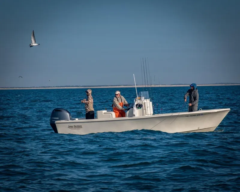 Slide: The Image of 2024 Jones Brothers Cape Fisherman 23 boat on calm water with cloudy sky. - 5