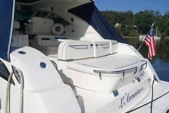 Slide: The Image of 2010 Sea Ray 470 Sundancer yacht with American flag, docked on a serene lake. - 14