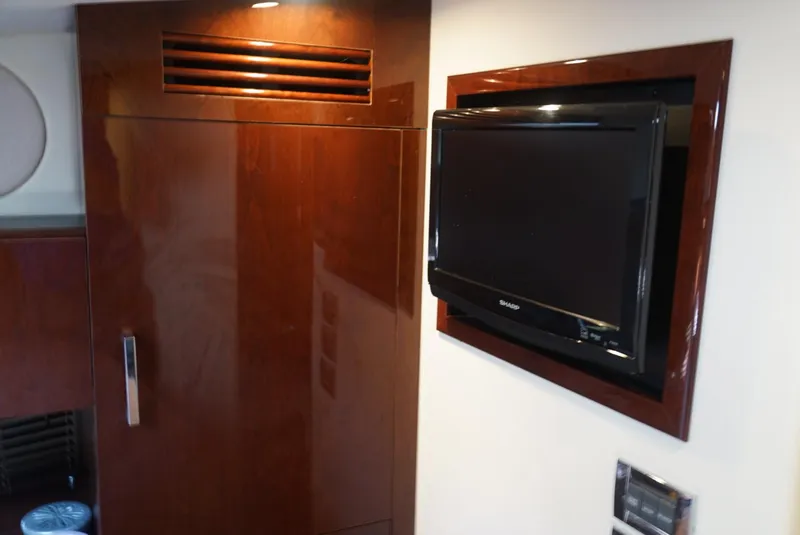 Slide: The Image of Luxury interior of 2010 Sea Ray 470 Sundancer with mounted TV and wooden cabinetry. - 18