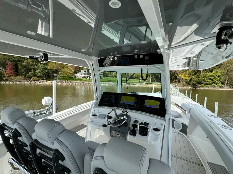 Slide: The Image of 2019 HCB Siesta boat interior with modern helm and seating, docked by a scenic lake. - 43