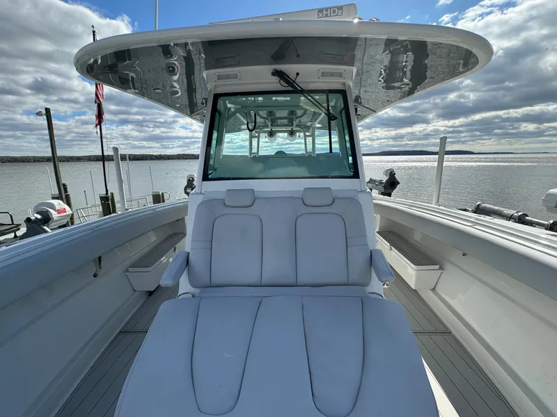 Slide: The Image of 2019 HCB Siesta boat with white seating, docked by a calm lake under a cloudy sky. - 23