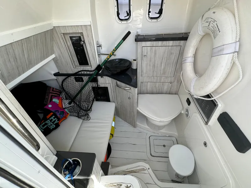 Slide: The Image of 2019 HCB Siesta boat interior with fishing gear, life preserver, and compact bathroom. - 26