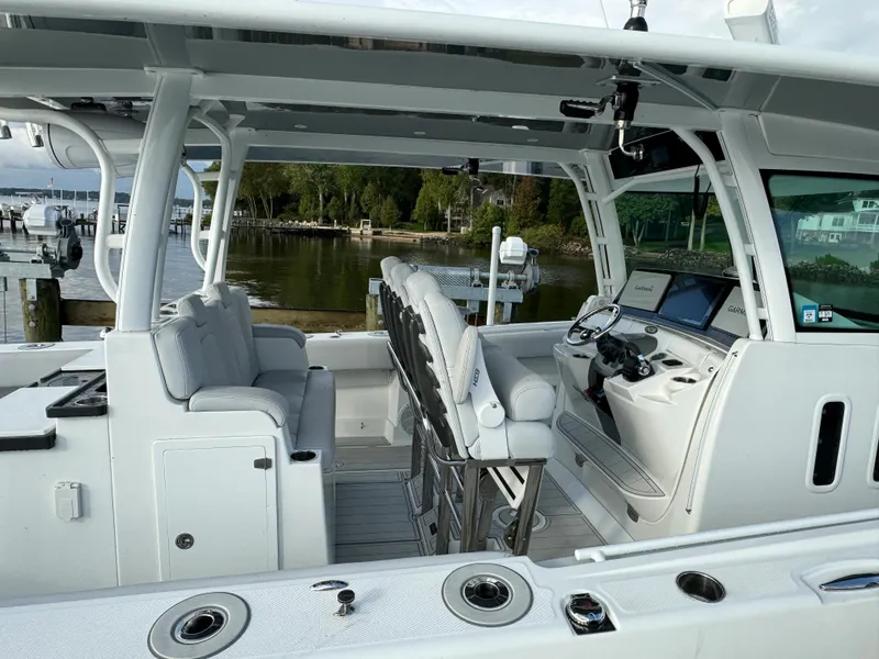 Slide: The Image of 2019 HCB Siesta boat interior with seating and control panel, docked by a serene waterfront. - 5
