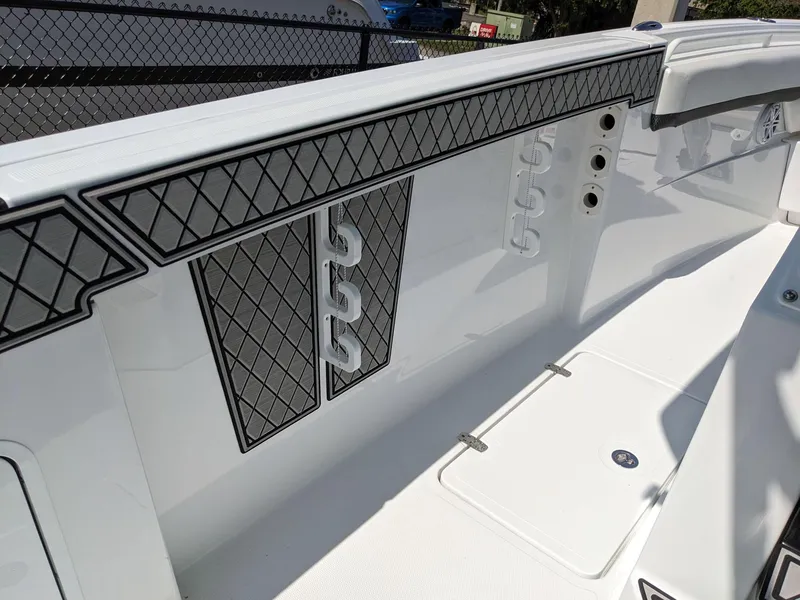 Slide: The Image of 2024 Wellcraft 302 Fisherman boat interior with rod holders and diamond-patterned padding. - 10