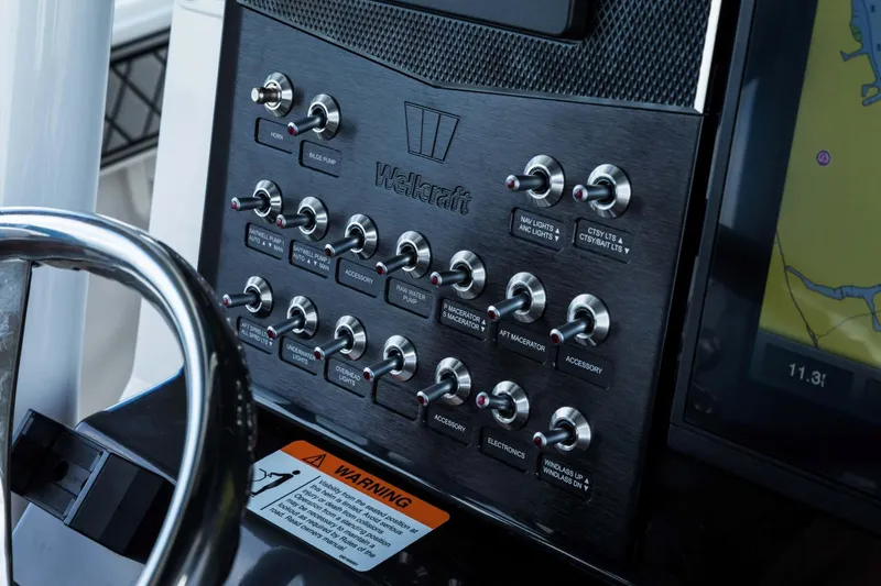 Slide: The Image of Control panel of 2024 Wellcraft 302 Fisherman boat with various switches and warning label. - 40