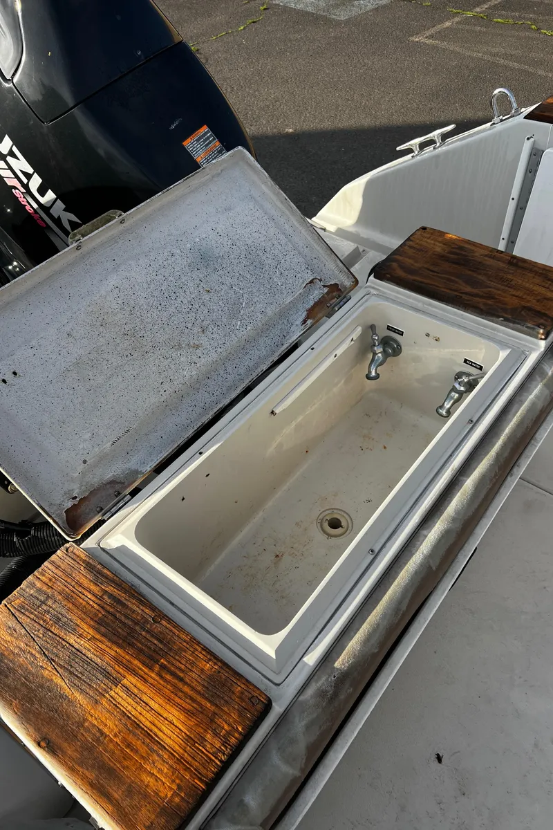 Slide: The Image of 1988 Sea Ray Laguna 23 boat with open storage compartment and Suzuki outboard motor. - 15