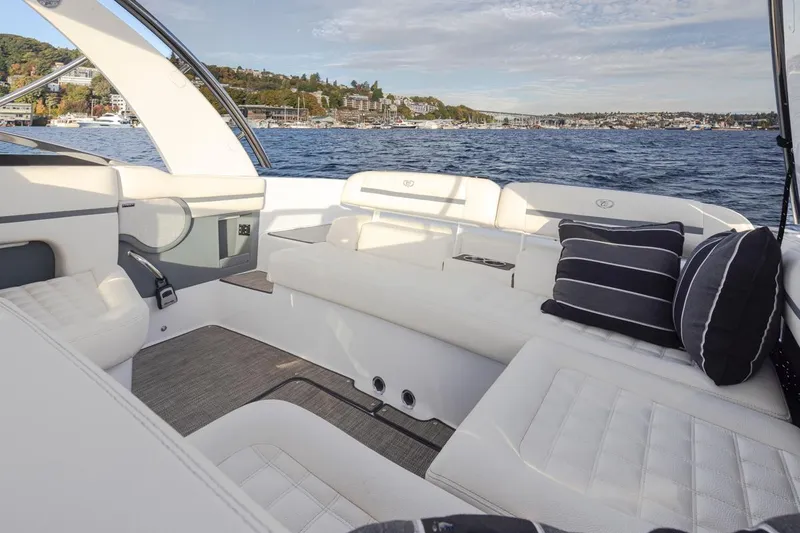 Slide: The Image of 2018 Cobalt 30 R boat interior with white seating and striped pillows on a lake. - 30