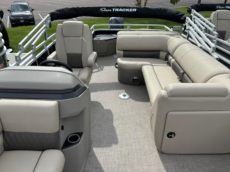 Slide: The Image of 2024 Sun Tracker SportFish 20 DLX pontoon boat interior with beige seating and helm. - 8