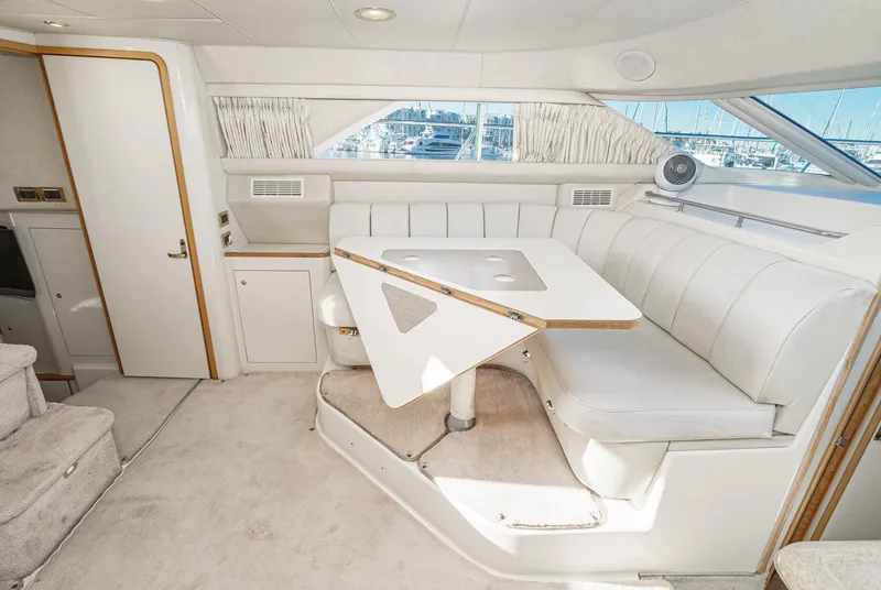 Slide: The Image of 1997 Sea Ray 420 Aft Cabin interior with white seating and dining area. - 34
