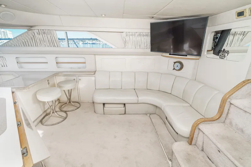 Slide: The Image of 1997 Sea Ray 420 Aft Cabin interior with curved sofa, bar stools, and mounted TV. - 40
