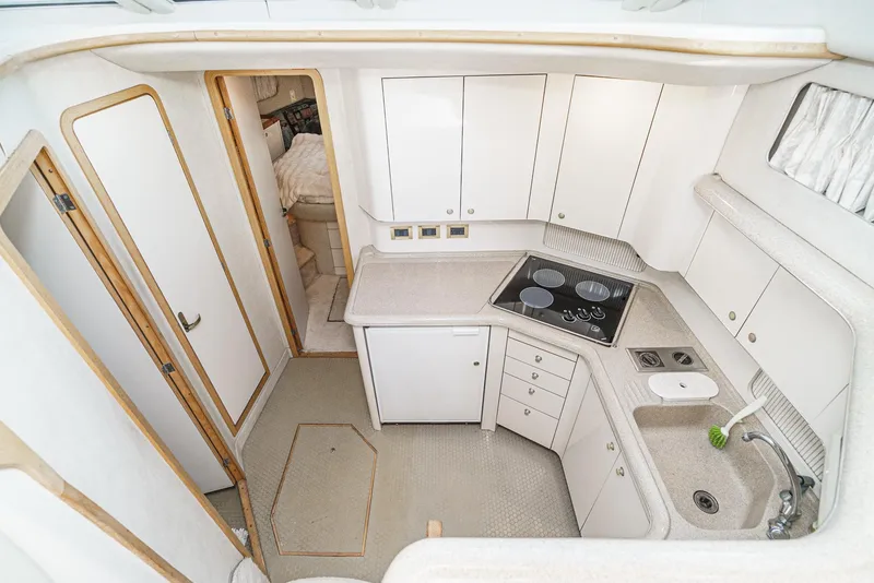 Slide: The Image of 1997 Sea Ray 420 Aft Cabin yacht kitchen with white cabinets and appliances. - 6