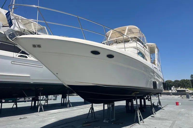 Slide: The Image of 1997 Sea Ray 420 Aft Cabin yacht on stands, viewed from the front, under clear blue sky. - 76