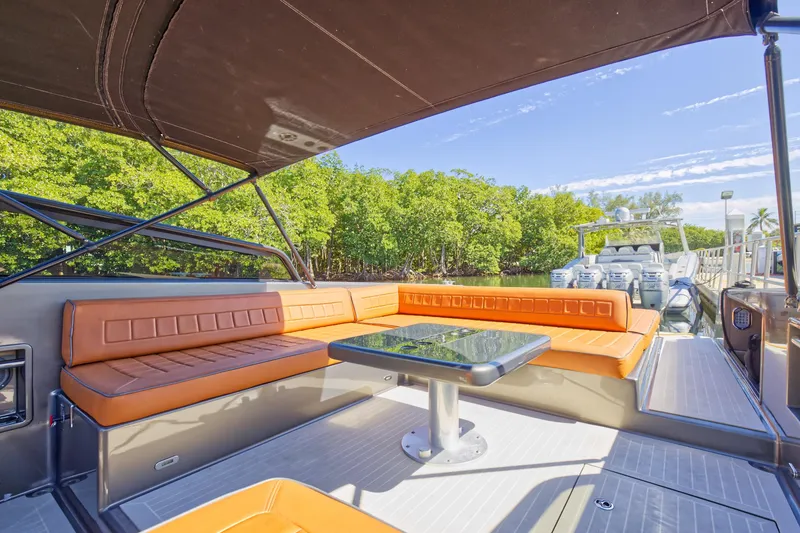 Slide: The Image of VanDutch 40 2015 yacht with orange seating and table, docked near lush greenery. - 24