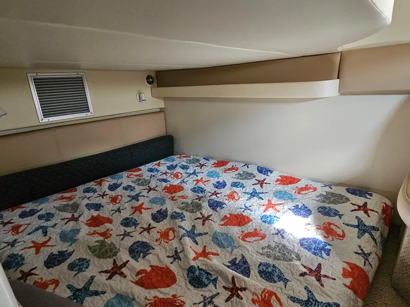 Slide: The Image of Interior cabin of a 2006 Bayliner 325 boat with a colorful sea-themed bedspread. - 12