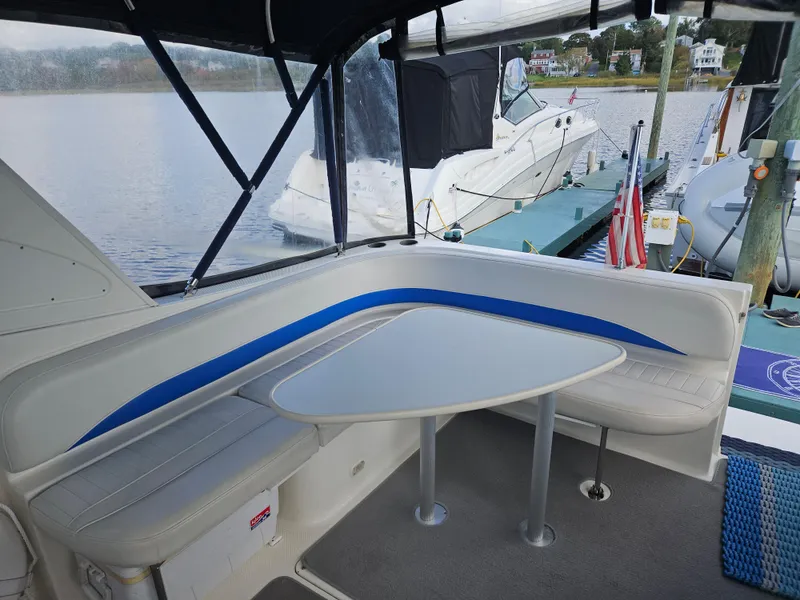 Slide: The Image of 2006 Bayliner 325 boat interior with seating and table, docked by the water. - 3