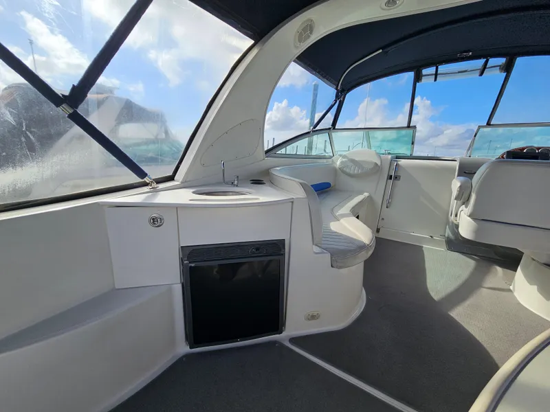Slide: The Image of 2006 Bayliner 325 interior with seating and kitchenette under blue canopy. - 5