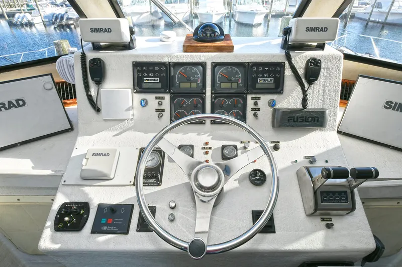 Slide: The Image of Control panel of a 2000 Torres 48 Enclosed Bridge boat with navigation instruments and steering wheel. - 12