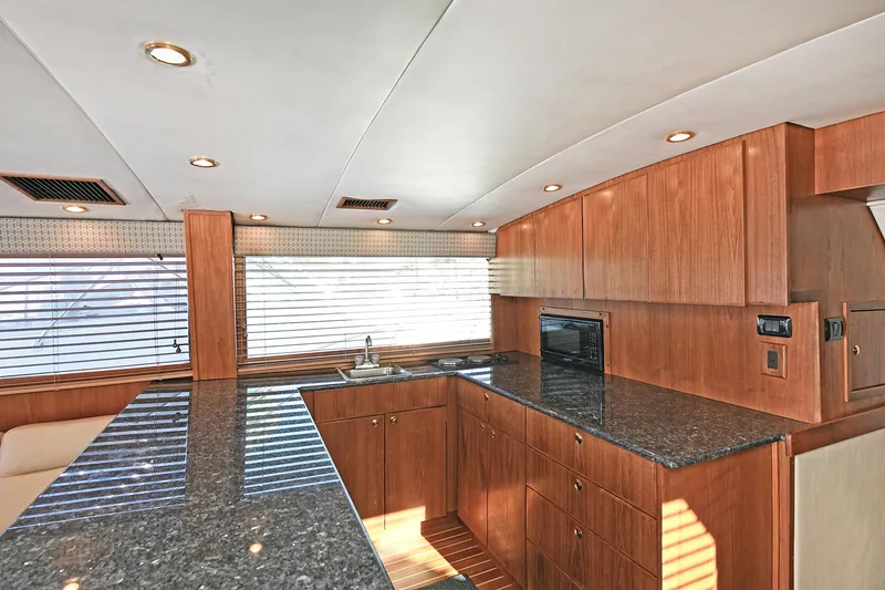 Slide: The Image of Luxurious kitchen interior of 2000 Torres 48 Enclosed Bridge yacht with wood cabinetry and granite countertops. - 23