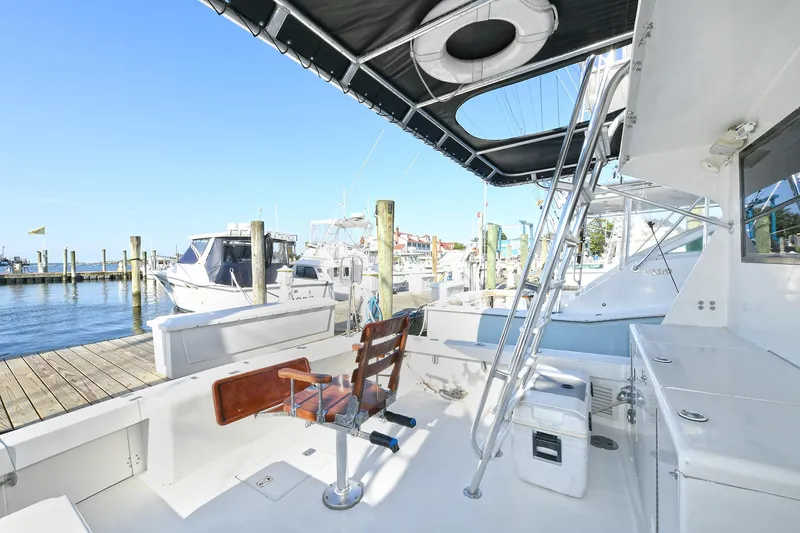 Slide: The Image of 2000 Torres 48 Enclosed Bridge yacht docked at marina, featuring spacious deck and seating. - 3