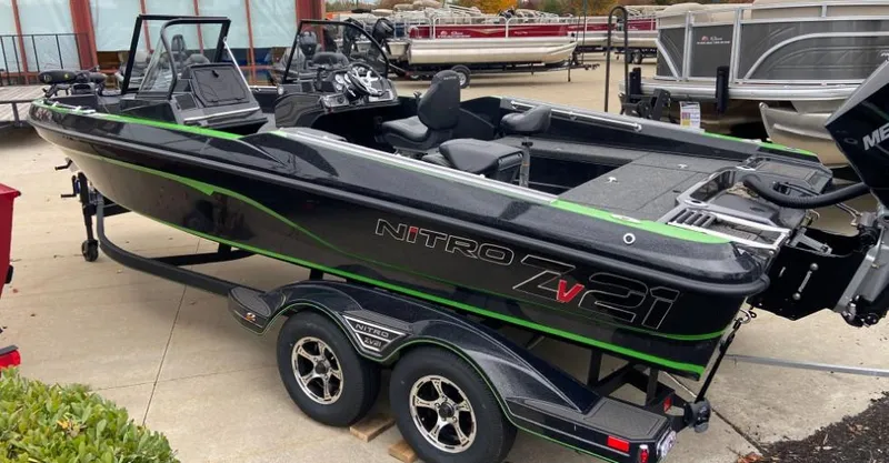 Slide: The Image of 2024 Nitro ZV21 fishing boat on a trailer, black with green accents. - 3