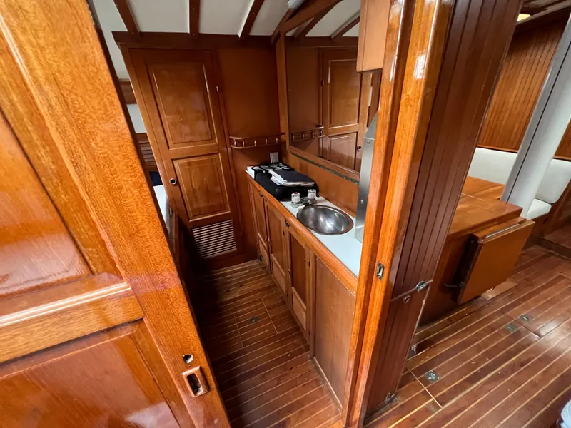 Slide: The Image of 1986 Krogen 38 yacht interior with wooden cabinetry and compact kitchen area. - 23