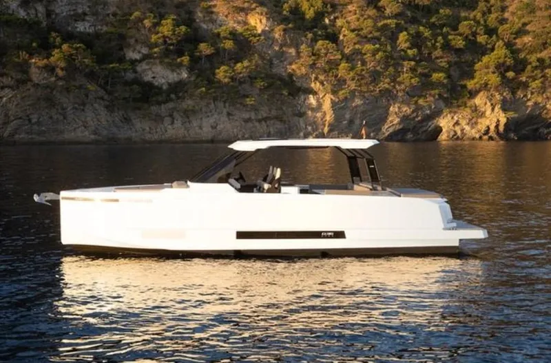 Slide: The Image of 2024 De Antonio Yachts D36 OPEN on serene water with rocky backdrop. - 0