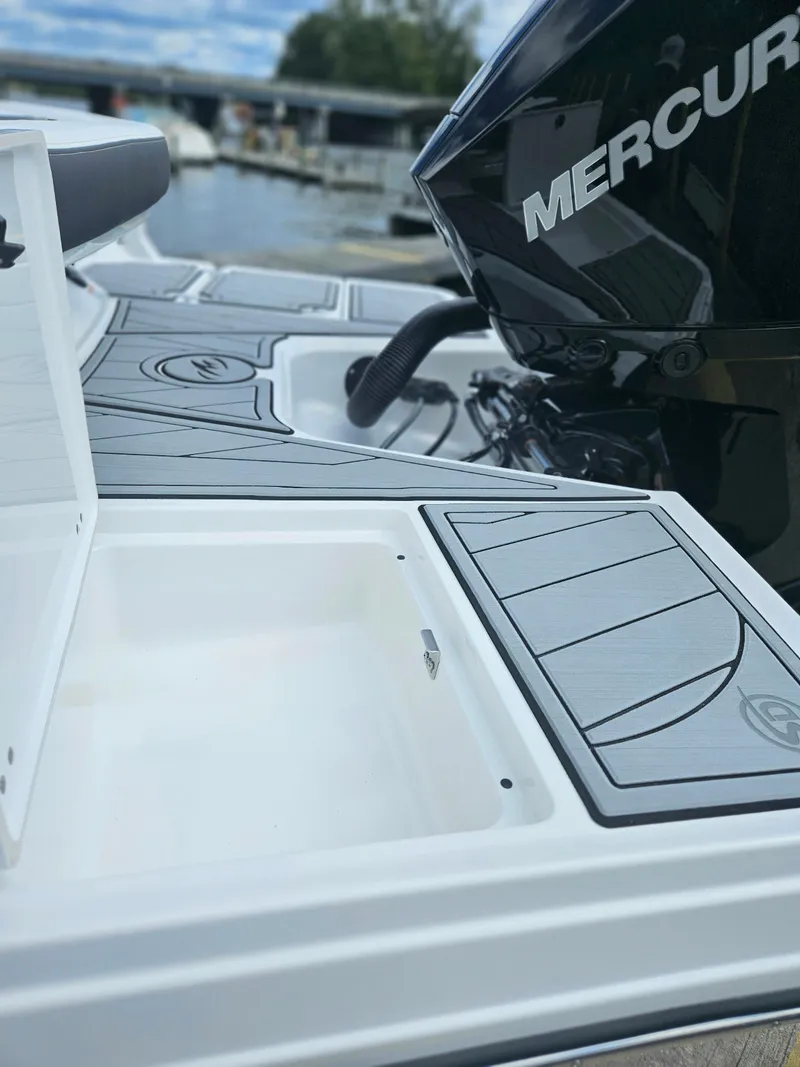 Slide: The Image of 2024 Monterey 215SS boat with Mercury engine, open storage compartment, docked by the water. - 10
