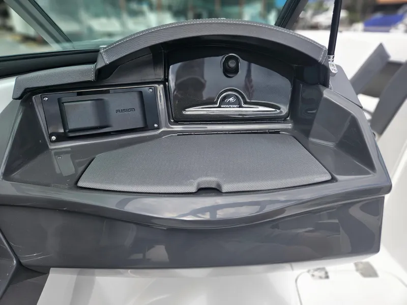 Slide: The Image of 2024 Monterey 215SS boat dashboard with storage compartments and Fusion audio system. - 23