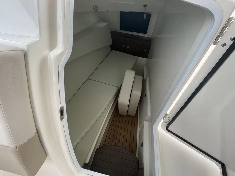 Slide: The Image of 2016 Boston Whaler 320 Vantage cabin interior with white seating and wooden flooring. - 21