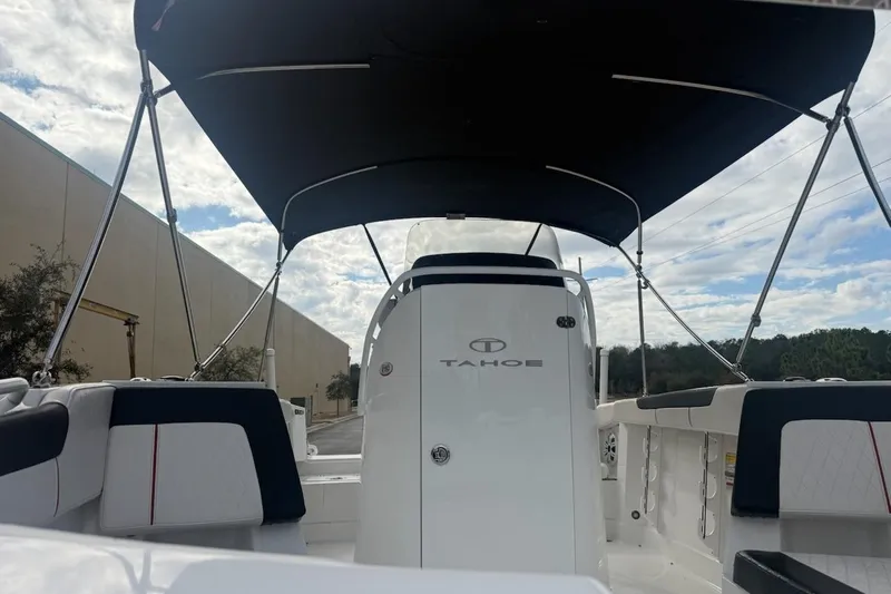 Slide: The Image of 2023 Tahoe 2150 boat interior with canopy, showcasing seating and helm under a cloudy sky. - 2