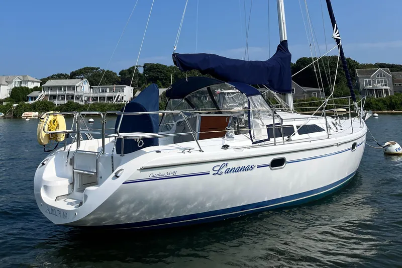 Slide: The Image of 2002 Catalina 34MK II sailboat anchored in scenic harbor with blue canopy. - 1