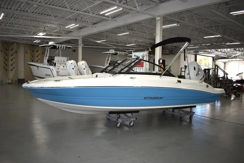 Slide: The Image of 2024 Stingray 191DC boat in showroom, blue and white hull, on display. - 2