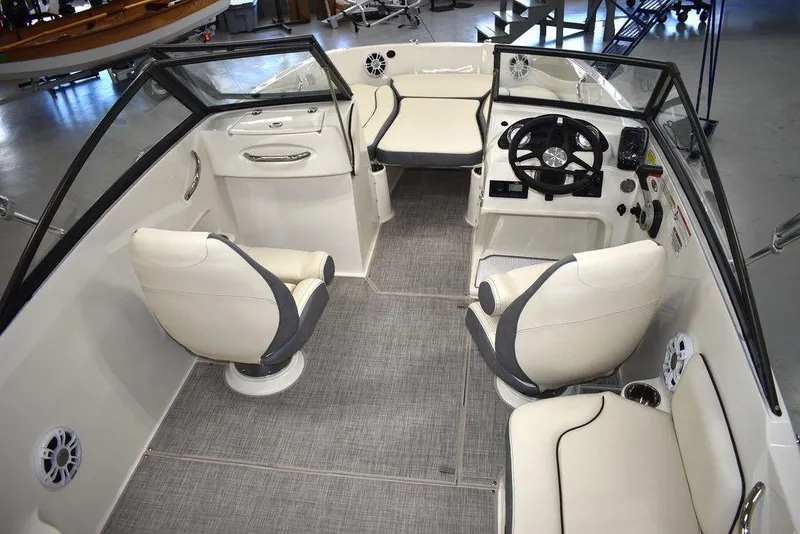 Slide: The Image of 2024 Stingray 191DC boat interior with white and gray seating, steering console, and carpeted floor. - 9