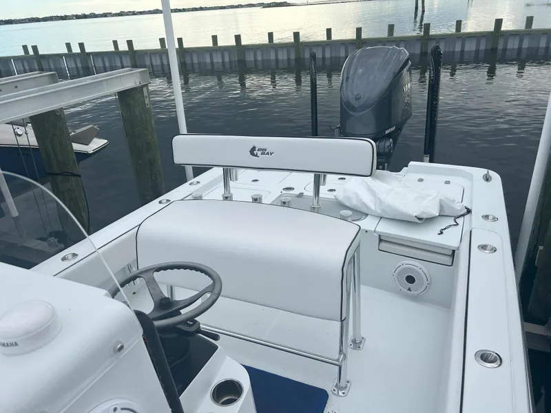 Slide: The Image of 2022 Contender 25 Bay boat docked, featuring a clean white interior and outboard motor. - 12