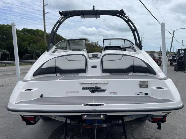 Slide: The Image of 2018 Yamaha Boats AR210, rear view, white and black, docked on trailer. - 5