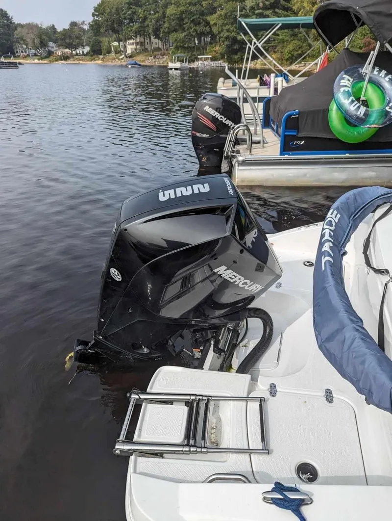 Slide: The Image of 2022 Tahoe 2150 boat with Mercury outboard motor docked on a calm lake. - 11