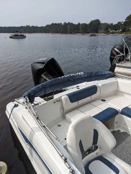 Slide: The Image of 2022 Tahoe 2150 boat docked on a calm lake with scenic background. - 7