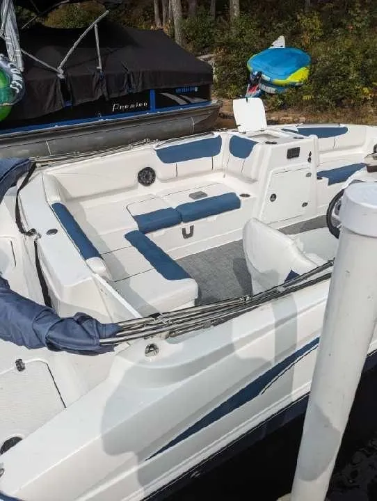 Slide: The Image of 2022 Tahoe 2150 boat with white and blue seating, docked near other boats. - 8