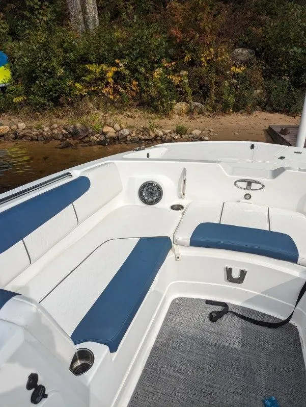 Slide: The Image of 2022 Tahoe 2150 boat interior with blue and white seating near a shoreline. - 9