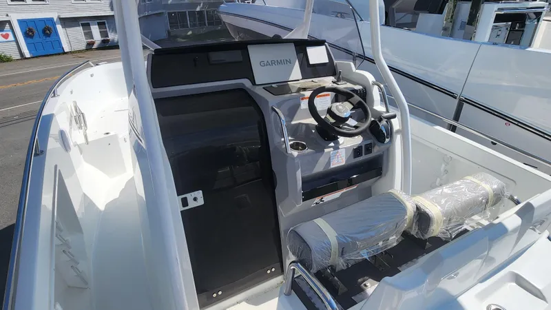 Slide: The Image of 2024 Jeanneau Leader 7.5 CC S3 boat with outboard motor docked near a scenic waterfront. - 23