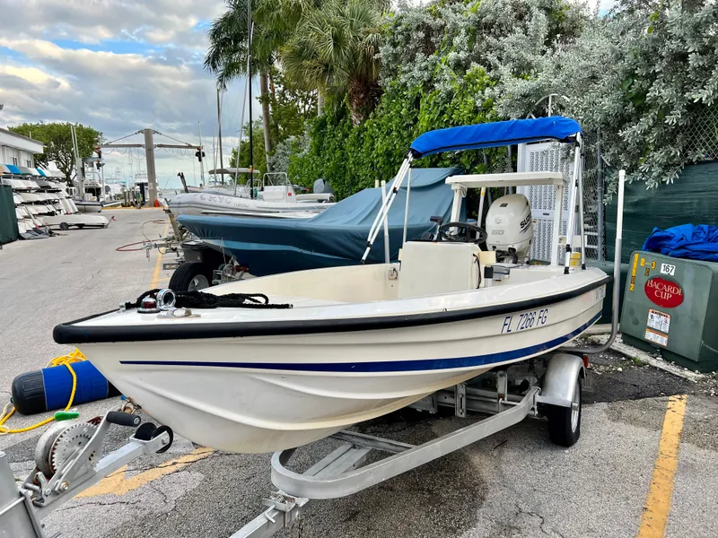 Slide: The Image of 1986 Hoog Comet 14 boat on trailer with blue canopy in marina. - 3