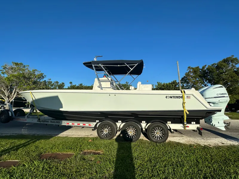 Slide: The Image of 2012 Contender 32 LS boat on a trailer with triple-axle wheels. - 0
